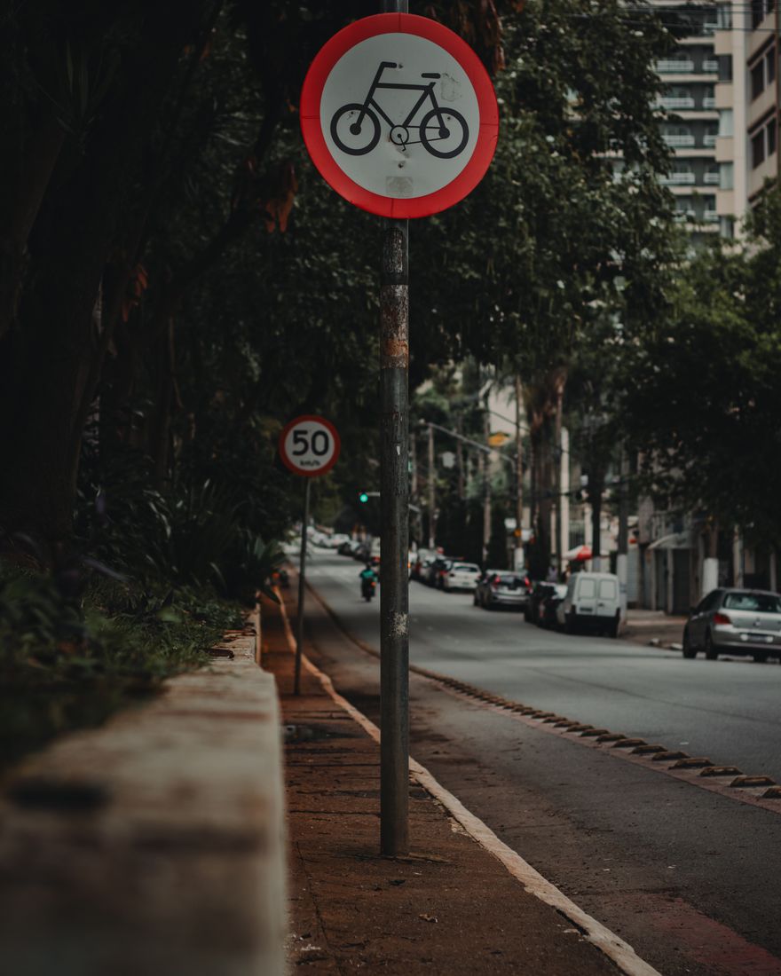 Placa de ciclovia numa rua arborizada